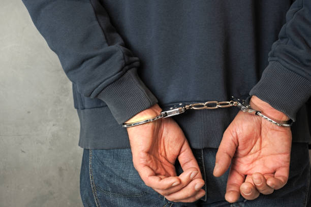 Hands of arrested man and handcuffs .