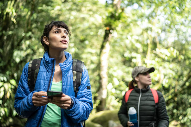 Women using smartphone in a forest during hiking