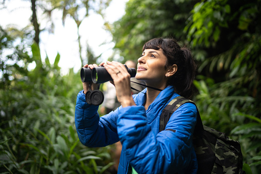 Young woman usng binoculars during hiking