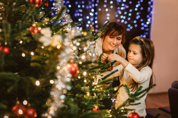 istock Girl decorating Christmas tree with mother looking at her 1316246183