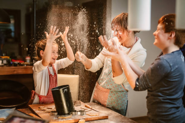 Family throwing flour and having fun while making cookies in kitchen Family throwing flour and having fun while making cookies in kitchen at home flour mess stock pictures, royalty-free photos & images