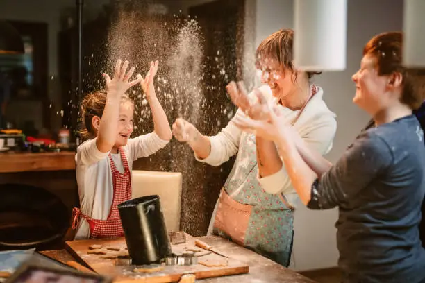 Family throwing flour and having fun while making cookies in kitchen at home