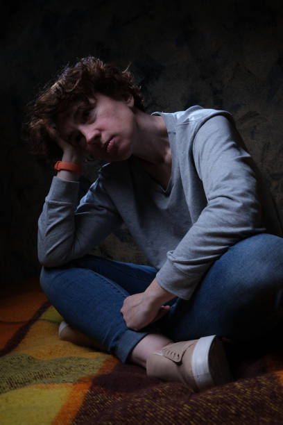 istock Distressed woman is sitting motionless on the sofa in dark room 1316251132