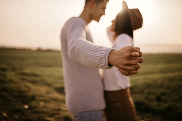 Closeup of loving couple holding hands and walking trought the vineyard. Happy lovers couple holding hands in spring. Mature couple in love walking in the summer park holding hands.