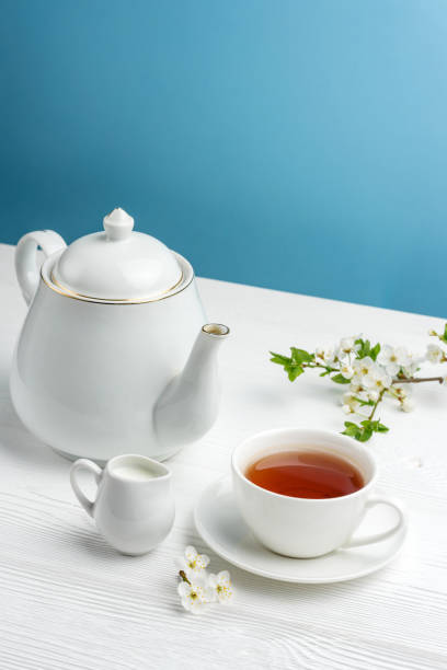 istock Teapot, tea cup, milk jug and cherry branch on a blue background 1316254014