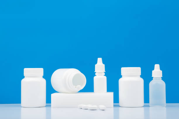 white medication bottles with pills, nose spray and eye drops on white table against blue background with copy space. - vibrant color healthcare and medicine healthy lifestyle vitamin pill imagens e fotografias de stock