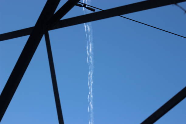 Photo of a Vapor trail from a plane through a electricity pylon creating an abstract picture