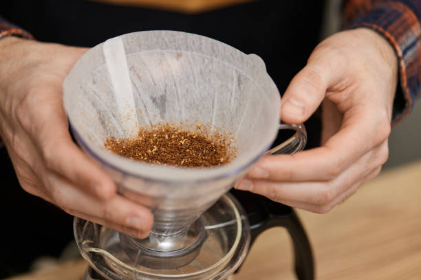 male hands pouring grounded coffee in filter.