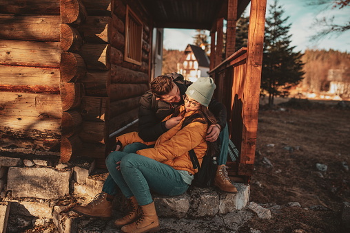 A loving man and woman are sitting on the balcony of their cottage