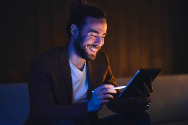 istock Happy man using tablet with stylus in darkness 1316264329