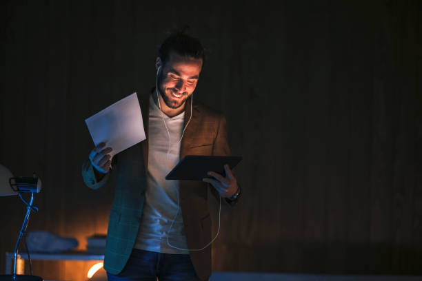 istock Joyful man with papers having video call in dark room 1316264340