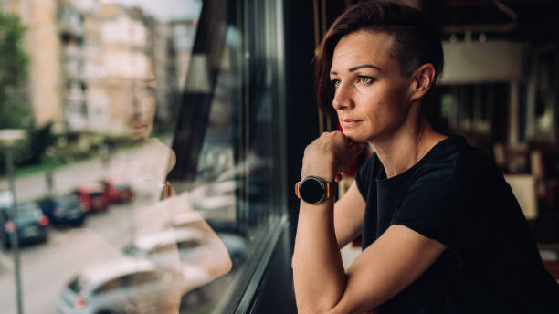 A woman in a black T-shirt sitting in a cafe by the window A woman in a black T-shirt sitting in a cafe by the window half shaved hairstyle stock pictures, royalty-free photos & images