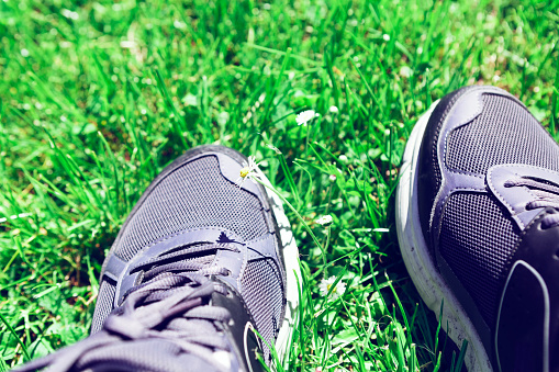 Sneakers on the grass . Trample nature on our feet