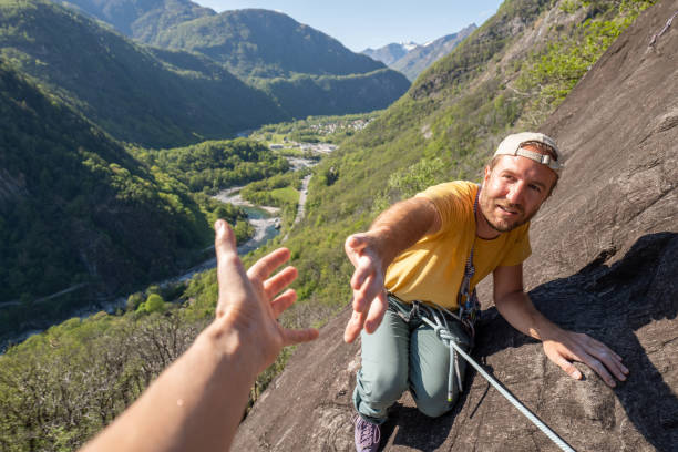 istock Man mountain climber reach out hand to get assistance from team mate 1316269616