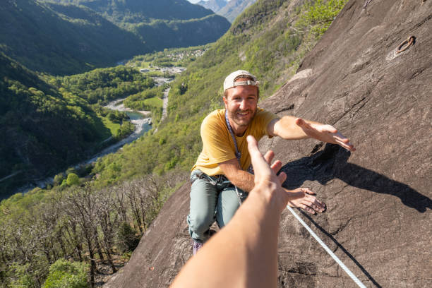 istock Man mountain climber reach out hand to get assistance from team mate 1316269620