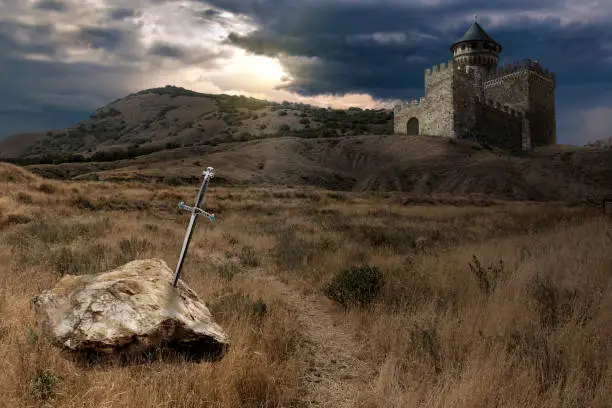 A collage on the theme of the legend of King Arthur and his sword Excalibur, sunk in stone. The image of the castle on the hill is a composite collage and is not a photo of a real castle.