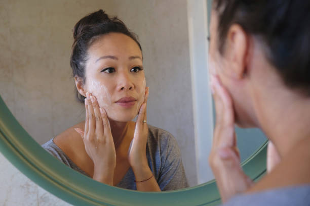 mujer indonesia lavándose la cara usando jabón limpiador de belleza - human face women mirror touching fotografías e imágenes de stock