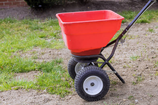 Sowing lawn grass seeds with a drop lawn spreader in the residential backyard Landscaping work sowing lawn grass seeds with a drop lawn spreader in the residential backyard lawn seeder stock pictures, royalty-free photos & images