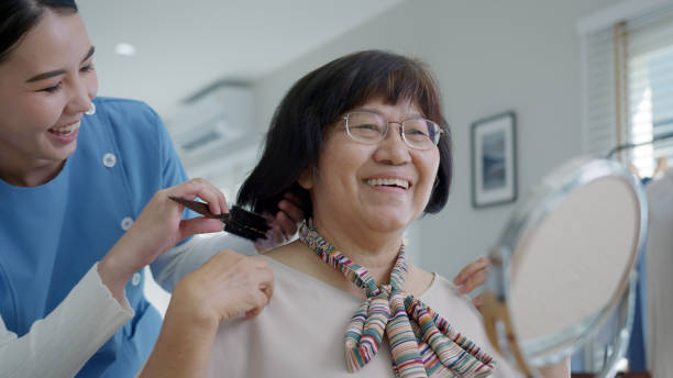 atractiva joven asiática senior mujer feliz cara con enfermera en casa en la mañana en estilo de vida de rutina, peinado cepillo de pelo, asia amamantando voluntaria en el hogar, concepto de servicio de vida asistida. - scrub brush fotografías e imágenes de stock