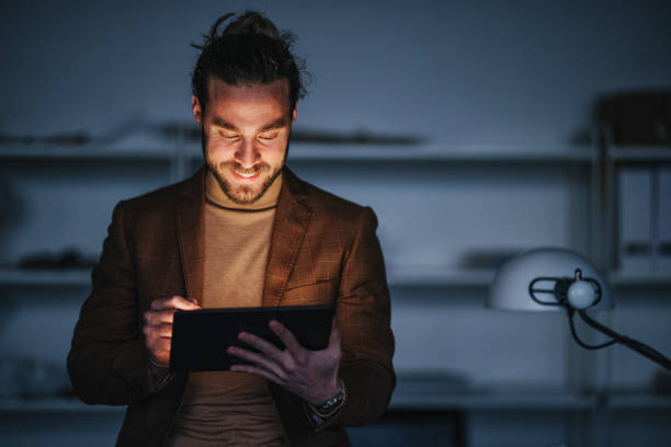 istock Cheerful man with tablet working on design project at night 1316277339