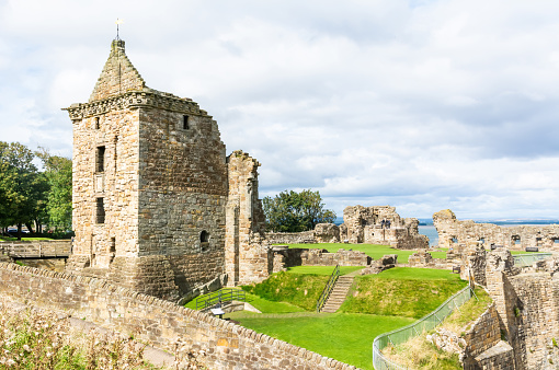 St Andrews, Scotland, United Kingdom - September 12, 2017.  Ruins of St Andrews Castle in the coastal Royal Burgh of St Andrews in Fife, Scotland. It was founded around 1200 as a fortified home for the bishop of St Andrews. View with people on a sunny day.