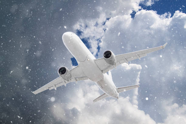 istock white passenger plane flies through falling snow against backdrop of beautiful ominous clouds on blue sky background in winter 1316278795