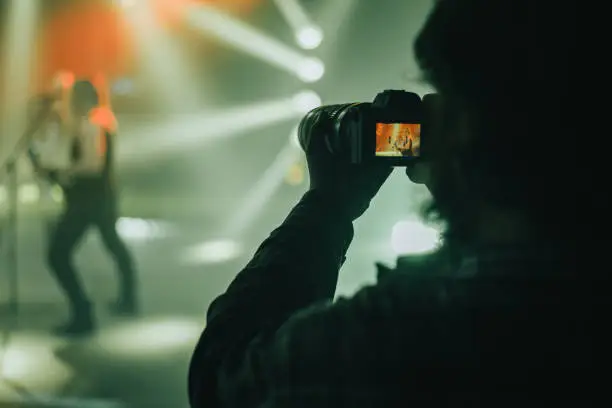 Photo of Silhouette of a photographer taking shots during a concert