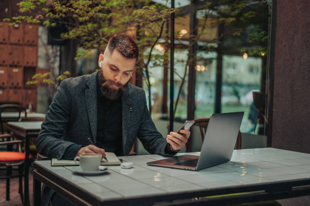 istock Businessman using a smartphone while working on a laptop in a cafe 1316280789