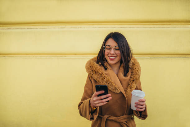 istock Hispanic woman using a smartphone and drinking coffee takeaway 1316280811
