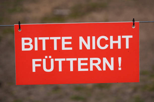 Red shield with white letters. Please do not feed. Instruction to ban feeding animals.