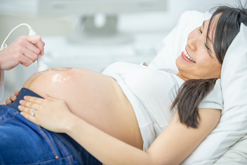 A pregnant woman smiles while receiving ultrasound test.
