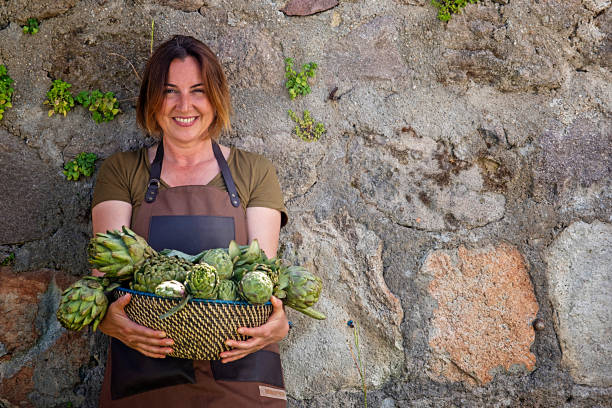 jeune femme heureuse posant et riant avec ses artichauts fraîchement moisson - beautiful smiling vegetable calcium photos et images de collection