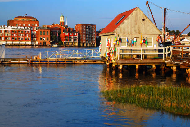 A small rustic fishing shack stands across more modern buildings in Portsmouth, New Hampshire