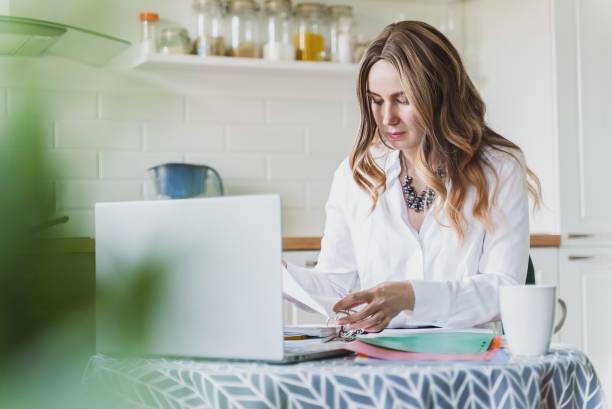 istock Woman works with documents in the kitchen at home. Self isolation concept. 1316288387