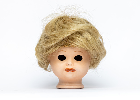 Doll's head without eyes against a white background