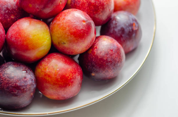 istock Closeup on fresh and ripe plums on a white ceramic plate 1316293964