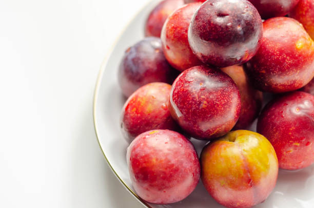 istock Closeup on fresh and ripe plums on a white ceramic plate 1316293967