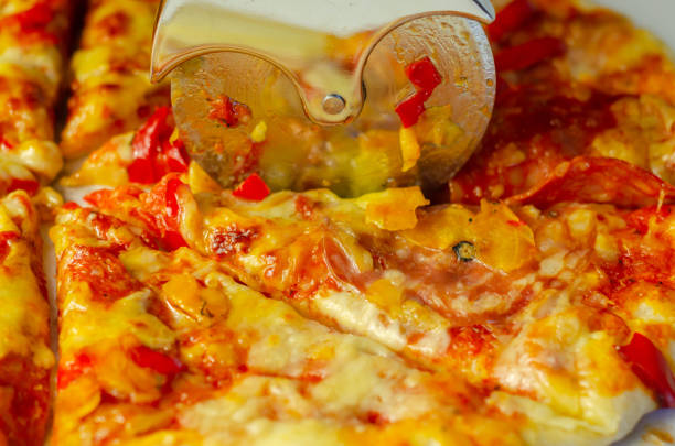 istock Cutting sourdought pizza base topped with tomato sauce, mozzarella and smoked cheddar cheeses, peppers, chorizo and salami 1316294170