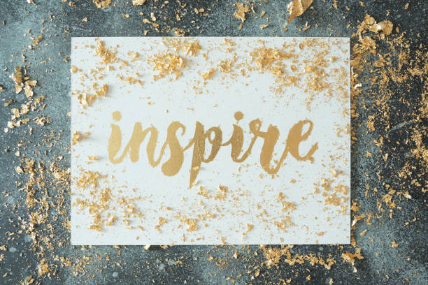 Inspire. Motivating lettering on white board. Handmade creativity. Gold letters. Gilding.