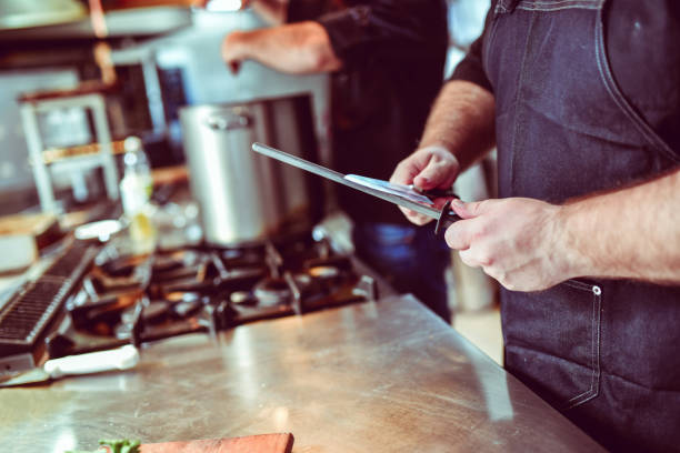istock Knife Sharpening In Modern Kitchen By Professional Cook 1316296325