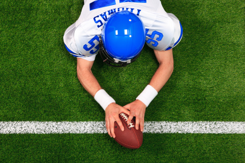 Overhead photo of an American football player making a touchdown with both hands on the ball. The uniform he's wearing is one I had made using my name and does not represent any actual team colours.