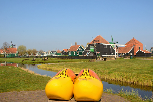 Zaanse schand-Netherlands; 20 -april / 2021: Aerial view looking over the Zaanse Schans. This is a public area with historic houses and Dutch windmills. In front is standing authentic xxl wooden clogs.