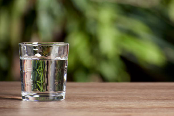 стеклянный стакан, полный воды на деревянном столе и естественном фоне - barware стоковые фото и изображения