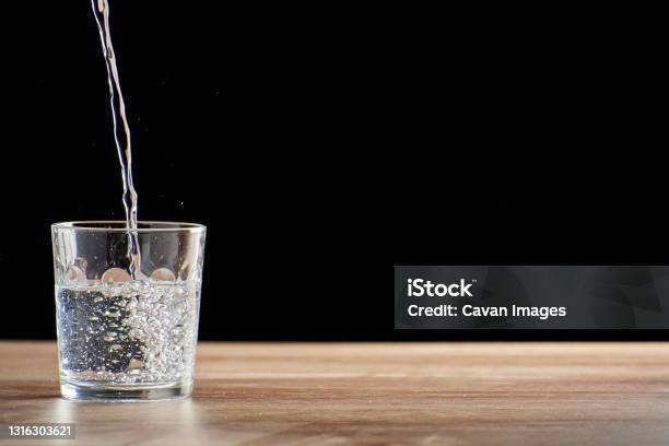 Szklany Kubek Nadziewany Wodą Na Drewnianym Stole I Czarnym Tle - zdjęcia stockowe i więcej obrazów Ica