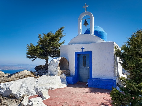 Pyrgos, Greece - September 12 2022: The traditional blue dome Greek Orthodox Holy Church of the Transfiguration of the Savior during golden hour in the quaint village of Pyrgos Kallistis on the island of Santorini.