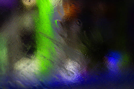 colorful texture created by rain and street lights on glass.\nthe texture created by the image of city lights from the car window on a rainy day.
