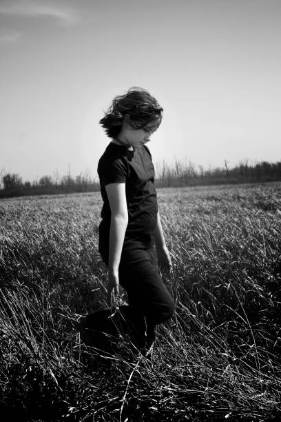 istock Little Girl Walking Through Marsh Grass Looking Down Full Length Black & White 1316309350