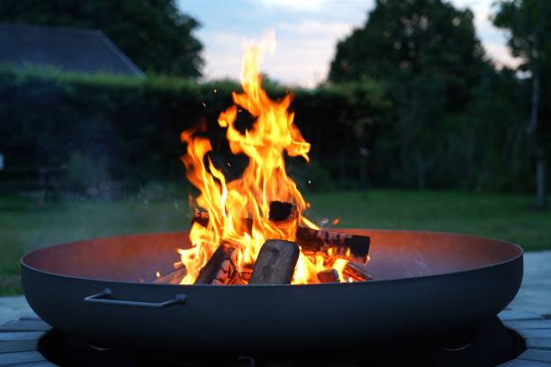 Iron fire pit and burning fire in a garden . Conceptual image . scandinavian fire pits stock pictures, royalty-free photos & images