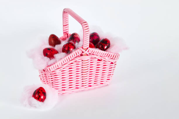 huevos de codorniz coloridos en una pequeña cesta de mimbre rosa sobre fondo blanco - wicker basket store gift shop fotografías e imágenes de stock