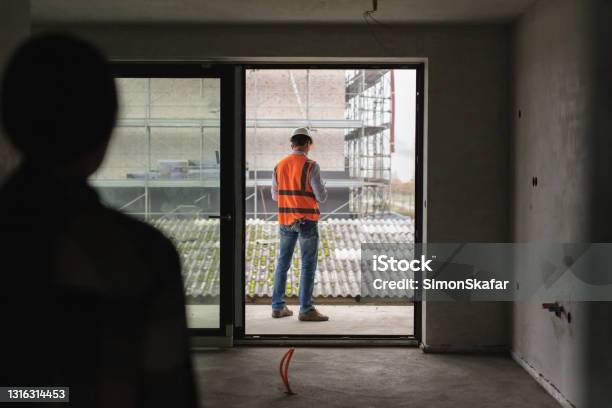 Customer With Architect Evaluating Work Inside An Under Construction Site Stock Photo - Download Image Now